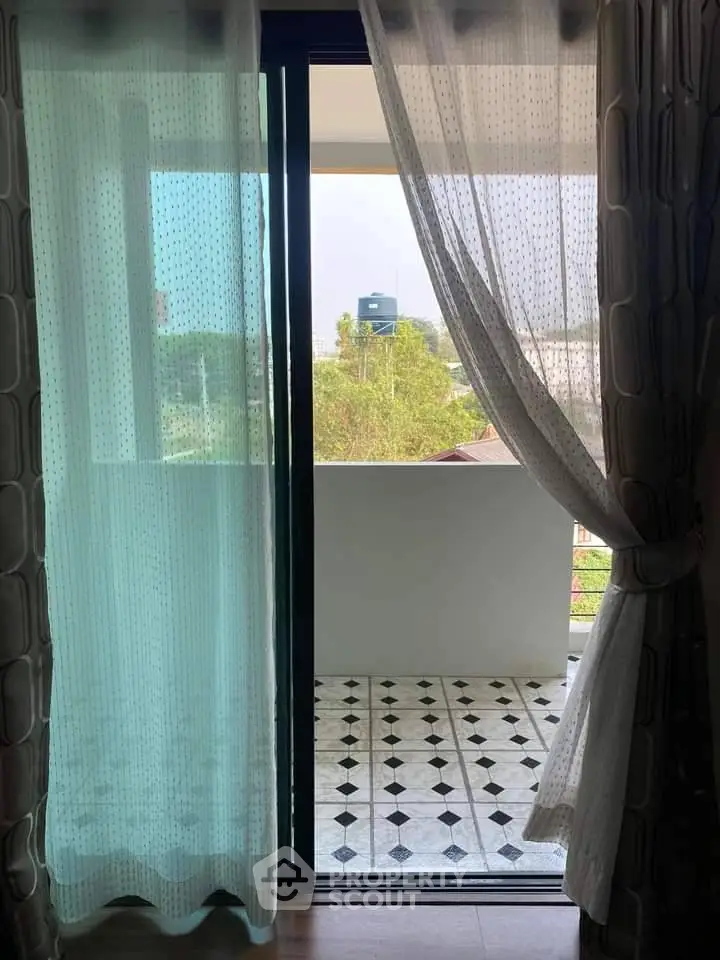 Charming balcony view with elegant curtains and patterned tile flooring.