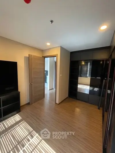 Modern bedroom with sleek wooden flooring and built-in wardrobe, perfect for urban living.