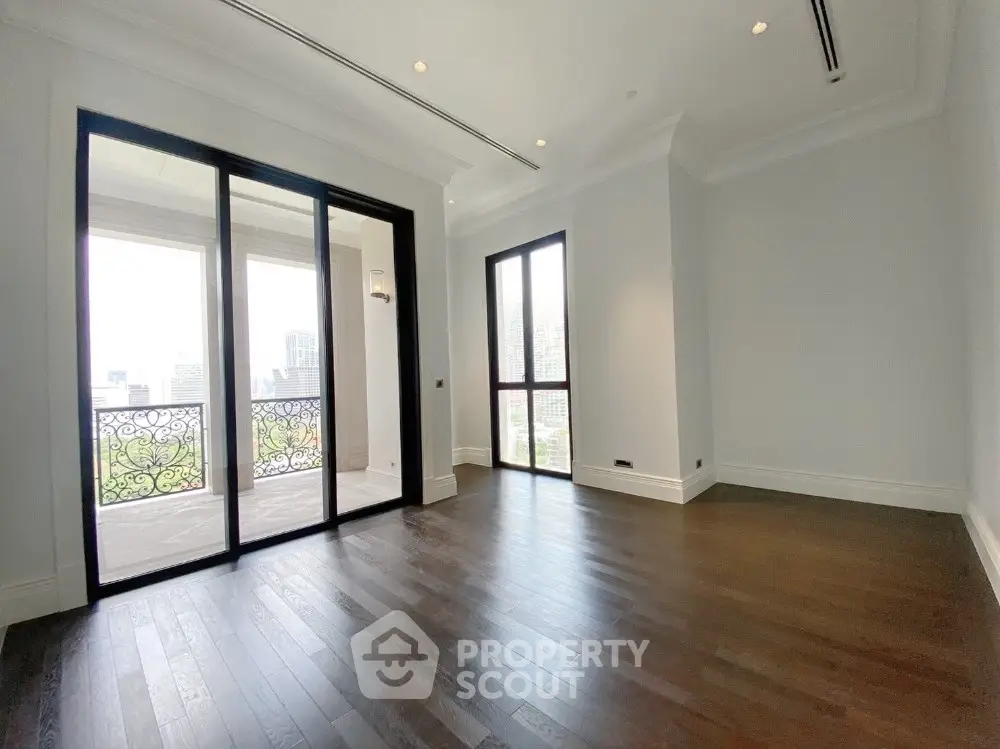 Spacious empty room with elegant balcony and hardwood floors