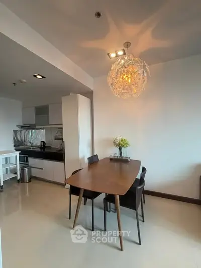 Modern dining area with stylish lighting and sleek kitchen design in open layout apartment.