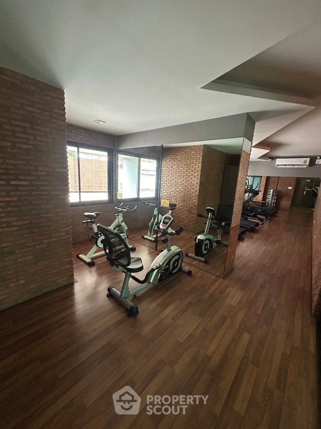 Modern gym with exercise bikes and treadmills in a stylish brick-walled fitness area.