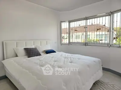 Bright bedroom with large windows and cozy white bedding in modern home.
