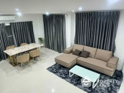 Modern living room with elegant sofa and dining area featuring marble table and stylish chairs.