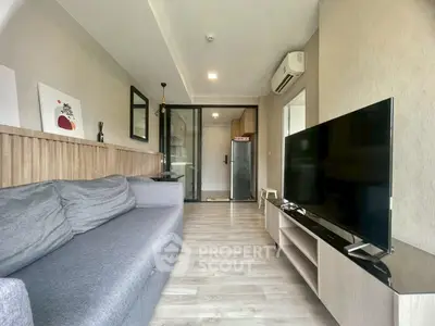 Modern living room with sleek furniture and large TV, open layout to kitchen