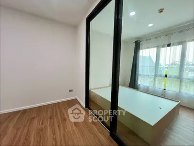 Modern bedroom with large window and wooden flooring, featuring a sleek glass partition.