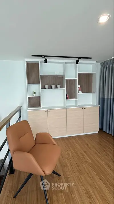 Modern living room with stylish shelving and comfortable chair on wooden flooring.