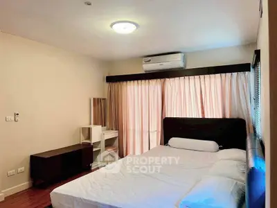 Spacious bedroom with modern furnishings and natural light, featuring a comfortable bed and air conditioning.