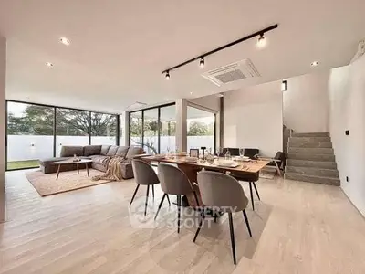 Spacious modern living room with open dining area and large windows.