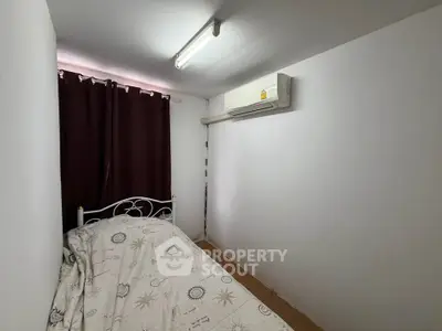 Cozy small bedroom with air conditioning and dark curtains, perfect for a restful sleep.