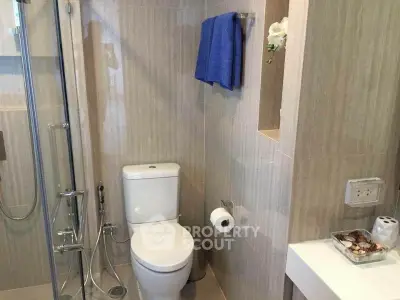 Modern bathroom with glass shower and sleek fixtures in contemporary apartment.