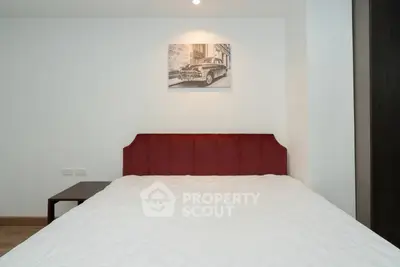 Cozy bedroom with stylish red headboard and vintage car artwork, perfect for modern living.