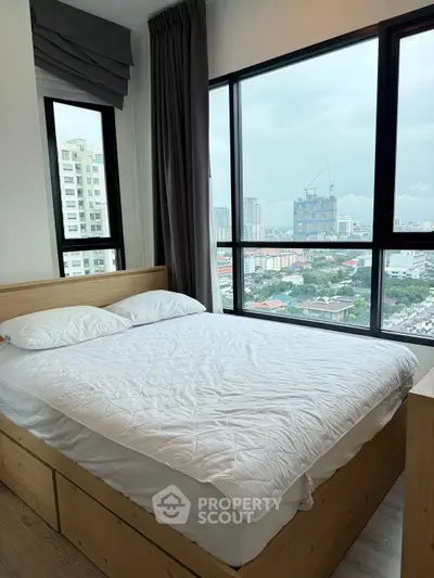 Modern bedroom with large windows offering stunning city views.