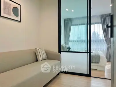Modern apartment with cozy living room and stylish bedroom separated by glass sliding door.