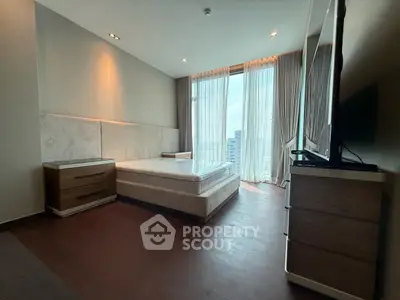 Spacious modern bedroom with large windows and city view, featuring elegant furnishings and natural light.