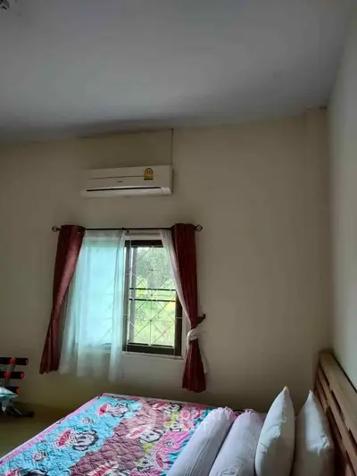 Cozy bedroom with air conditioning and colorful bedding, featuring a window with natural light.