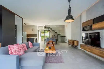 Modern open-plan living room with stylish decor and large TV, perfect for entertaining.