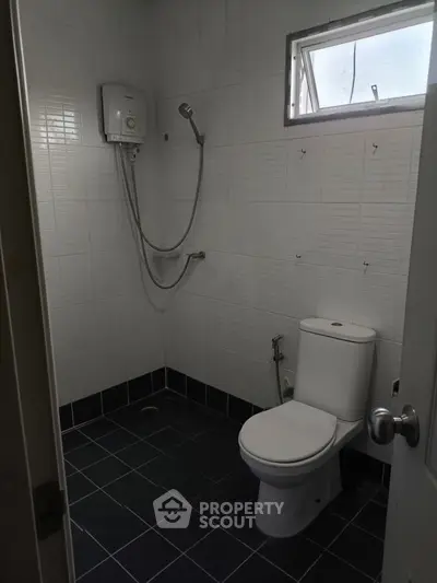 Compact bathroom with shower and toilet, featuring modern tiled walls and flooring.