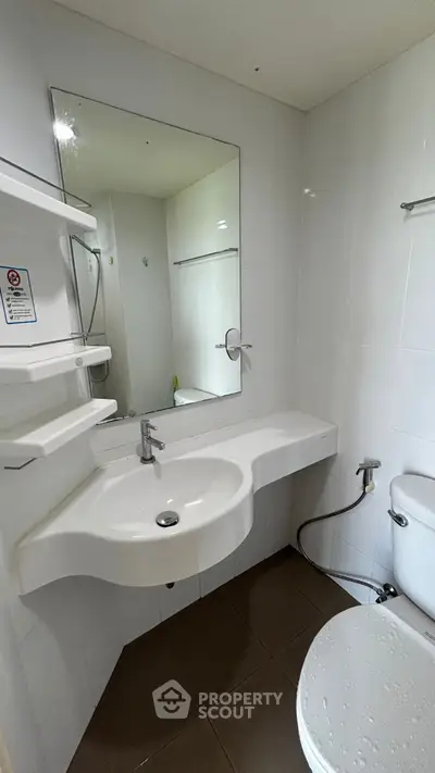 Modern bathroom with sleek white fixtures and large mirror