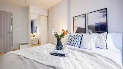 Stylish bedroom with modern decor and cozy ambiance, featuring elegant artwork and plush bedding.
