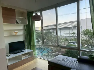 Modern living room with large windows and garden view, featuring stylish furniture and natural light.