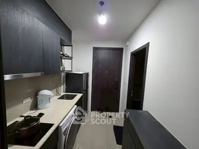 Compact modern kitchen with sleek cabinetry and appliances in a cozy apartment.