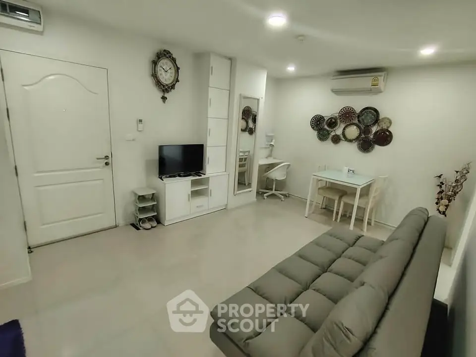 Modern living room with sleek furniture and wall-mounted TV in a cozy apartment.