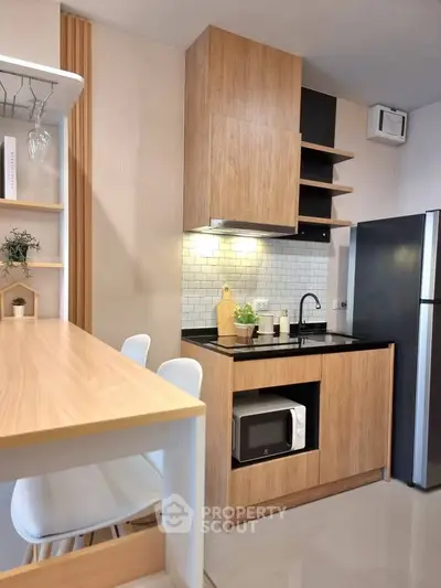 Modern kitchen with wooden cabinets, sleek black countertop, and built-in microwave in a cozy apartment.