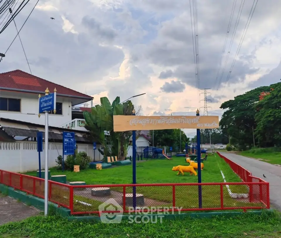 Charming suburban park with playground and lush greenery under a cloudy sky.