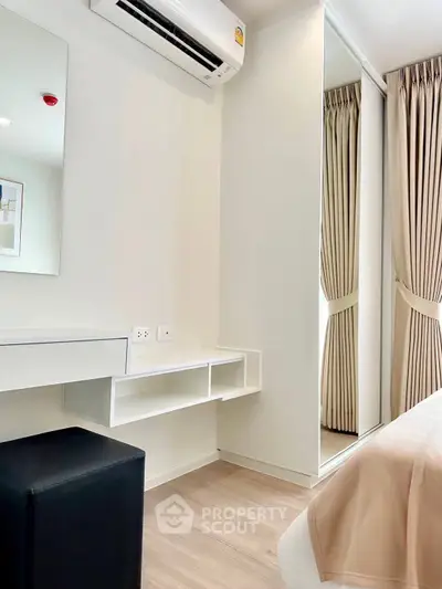Modern bedroom with sleek design, featuring mirrored wardrobe and air conditioning unit.