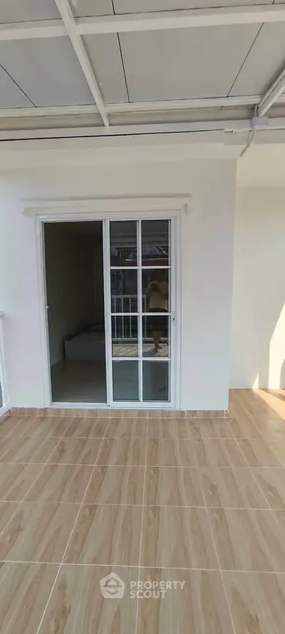 Spacious balcony with sliding glass doors and tiled flooring, perfect for outdoor relaxation.