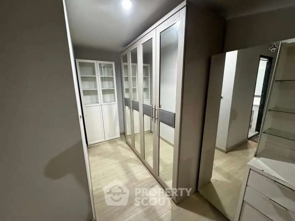 Spacious walk-in closet with mirrored wardrobes and ample storage space.