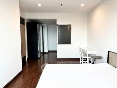 Spacious bedroom with modern design and wooden flooring, featuring a study area and ample closet space.