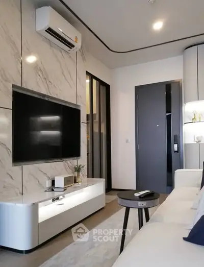 Modern living room with sleek design, featuring a wall-mounted TV, air conditioning, and stylish furniture.