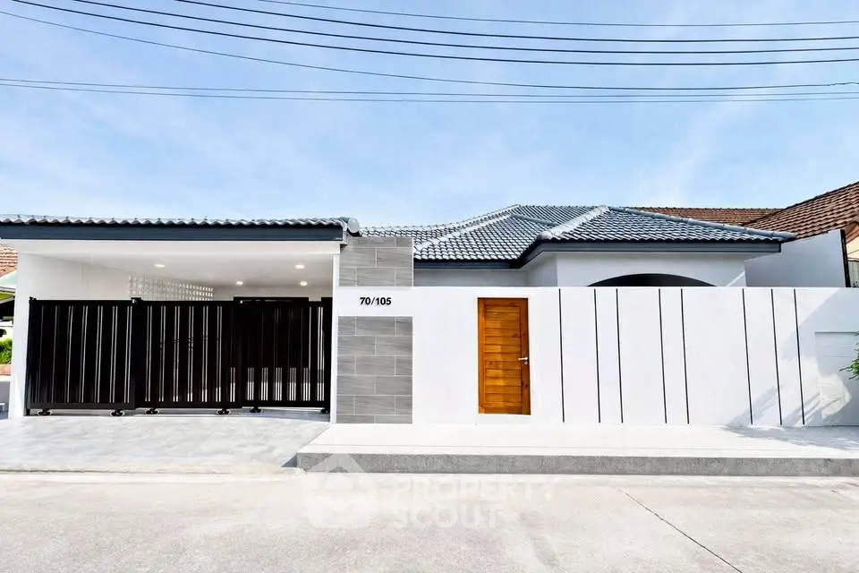 Modern single-story house with sleek design and gated entrance in a suburban neighborhood.