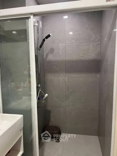 Modern bathroom with sleek gray tiles and glass shower enclosure