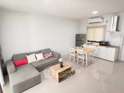 Modern open-layout living room with sleek kitchen and cozy seating area.