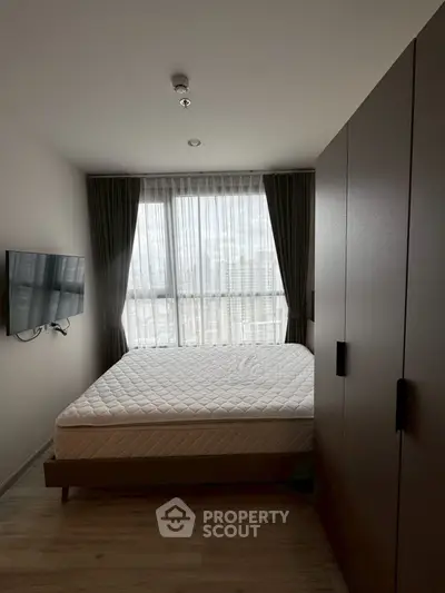 Cozy bedroom with large window and modern furnishings in urban apartment