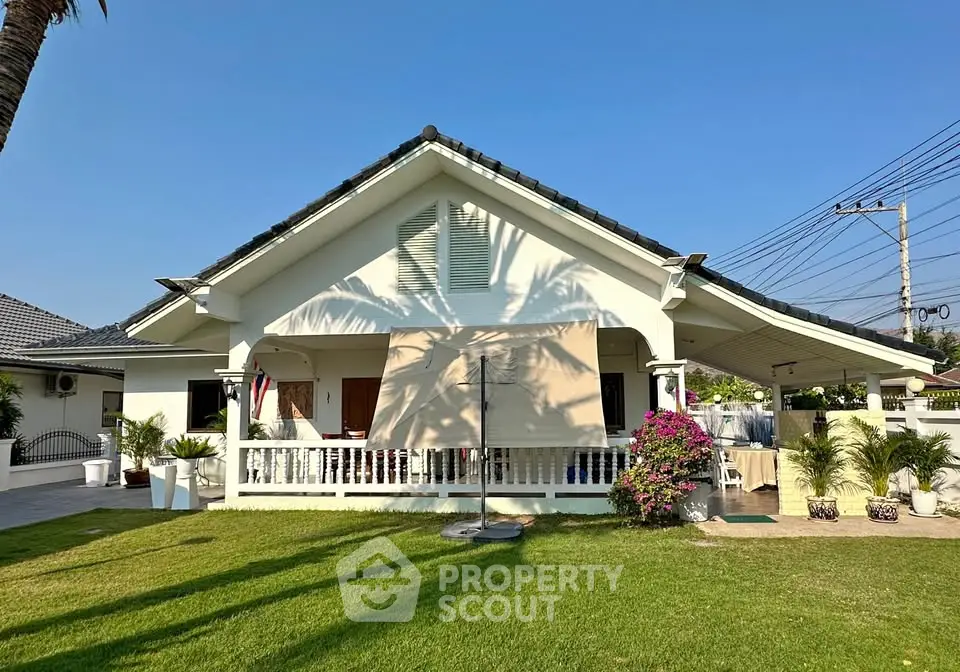 Charming single-story house with lush garden and spacious front porch.