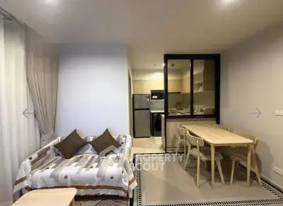 Modern living room with cozy sofa, dining area, and sleek kitchen featuring appliances.