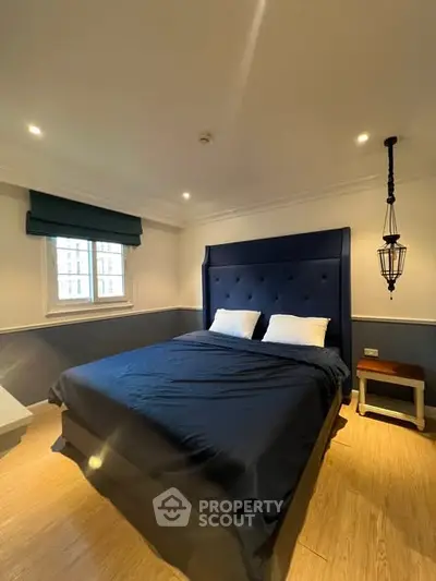 Cozy bedroom with elegant navy blue bed and modern lighting