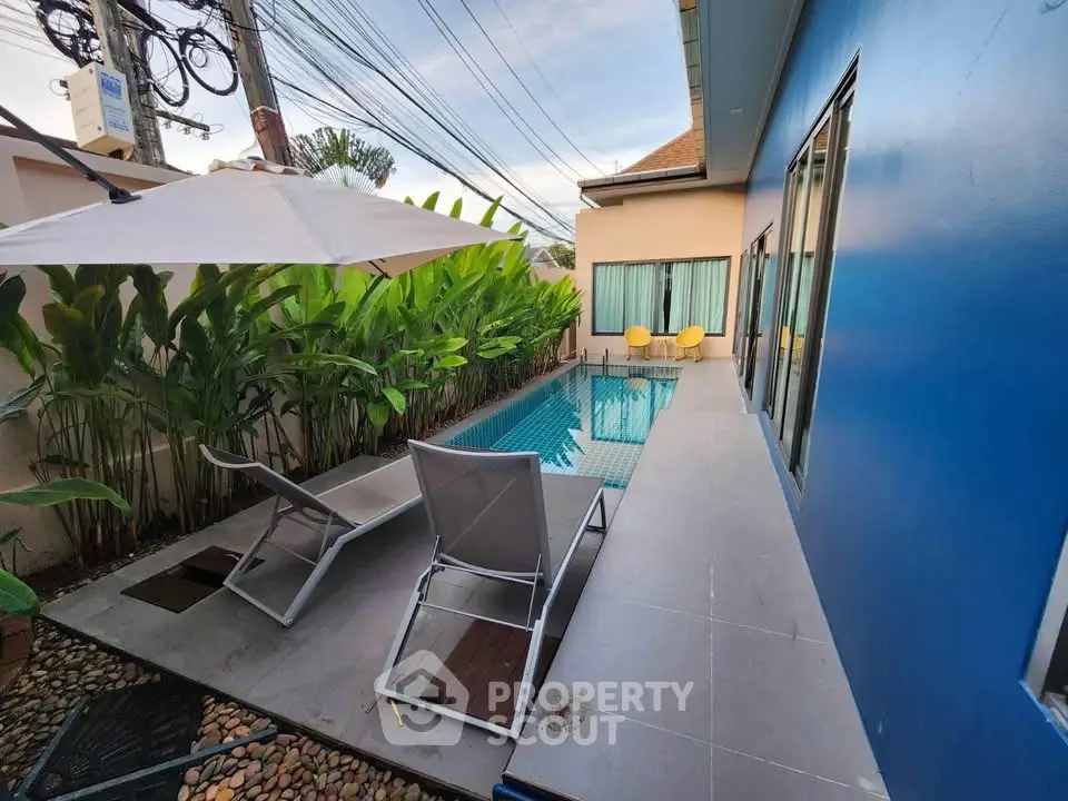 Charming private pool area with modern lounge chairs and lush greenery, perfect for relaxation.