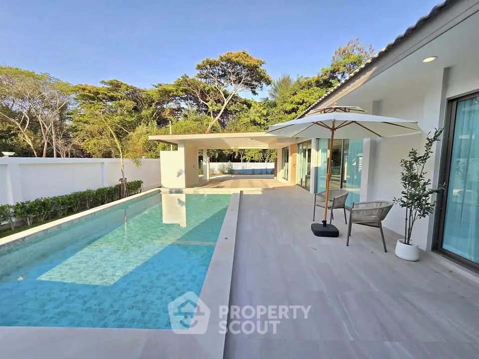 Luxurious modern villa with private pool and spacious patio, surrounded by lush greenery, perfect for relaxation.