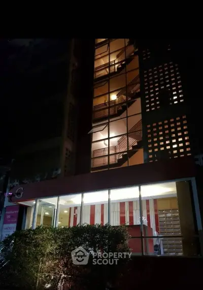 Modern building exterior with illuminated stairwell and glass facade at night.
