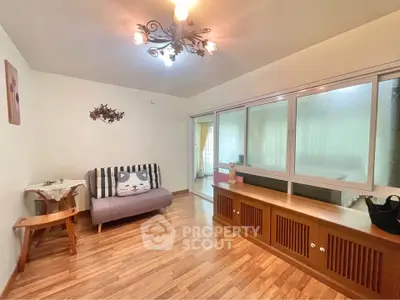 Charming living room with wooden flooring and cozy decor, featuring a unique panda-themed sofa and elegant lighting.