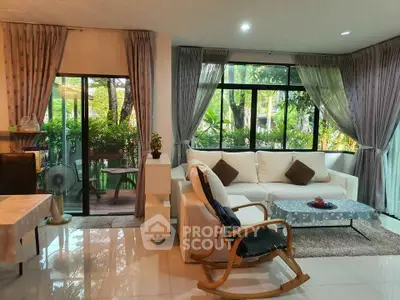 Spacious living room with large windows and garden view, featuring cozy seating and elegant decor.