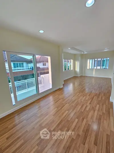 Spacious and bright living room with wooden flooring and large windows.