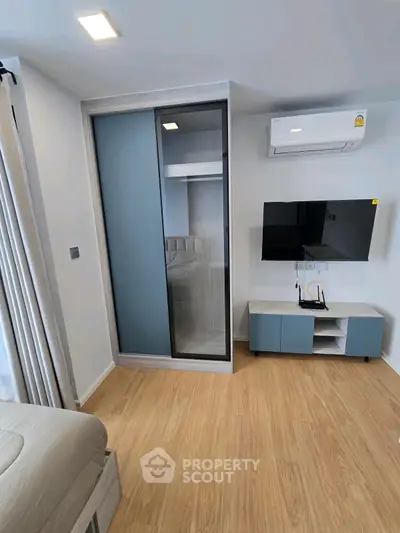 Modern bedroom with sleek design, featuring built-in wardrobe and wall-mounted TV.