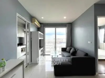 Modern living room with sleek furniture and large window offering city view