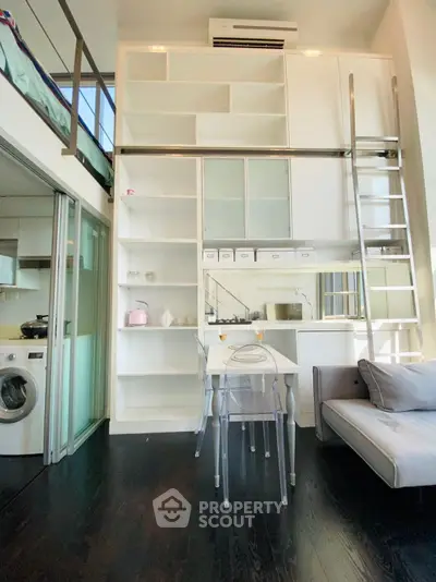 Modern loft apartment with high ceilings, built-in shelves, and compact dining area.