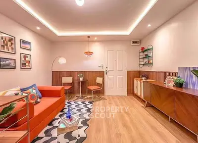 Stylish living room with modern decor, vibrant orange sofa, and elegant lighting in a cozy apartment.